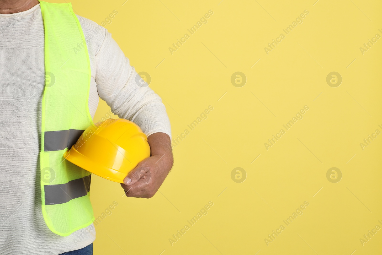 Photo of Engineer with hard hat on yellow background, closeup. Space for text