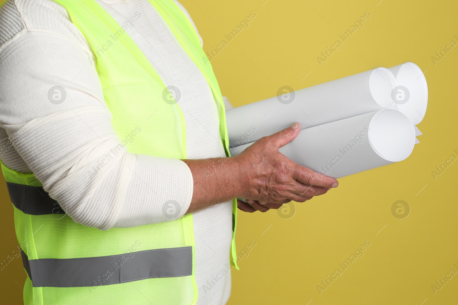 Photo of Engineer with drafts on yellow background, closeup