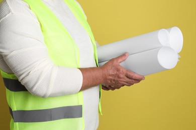 Photo of Engineer with drafts on yellow background, closeup