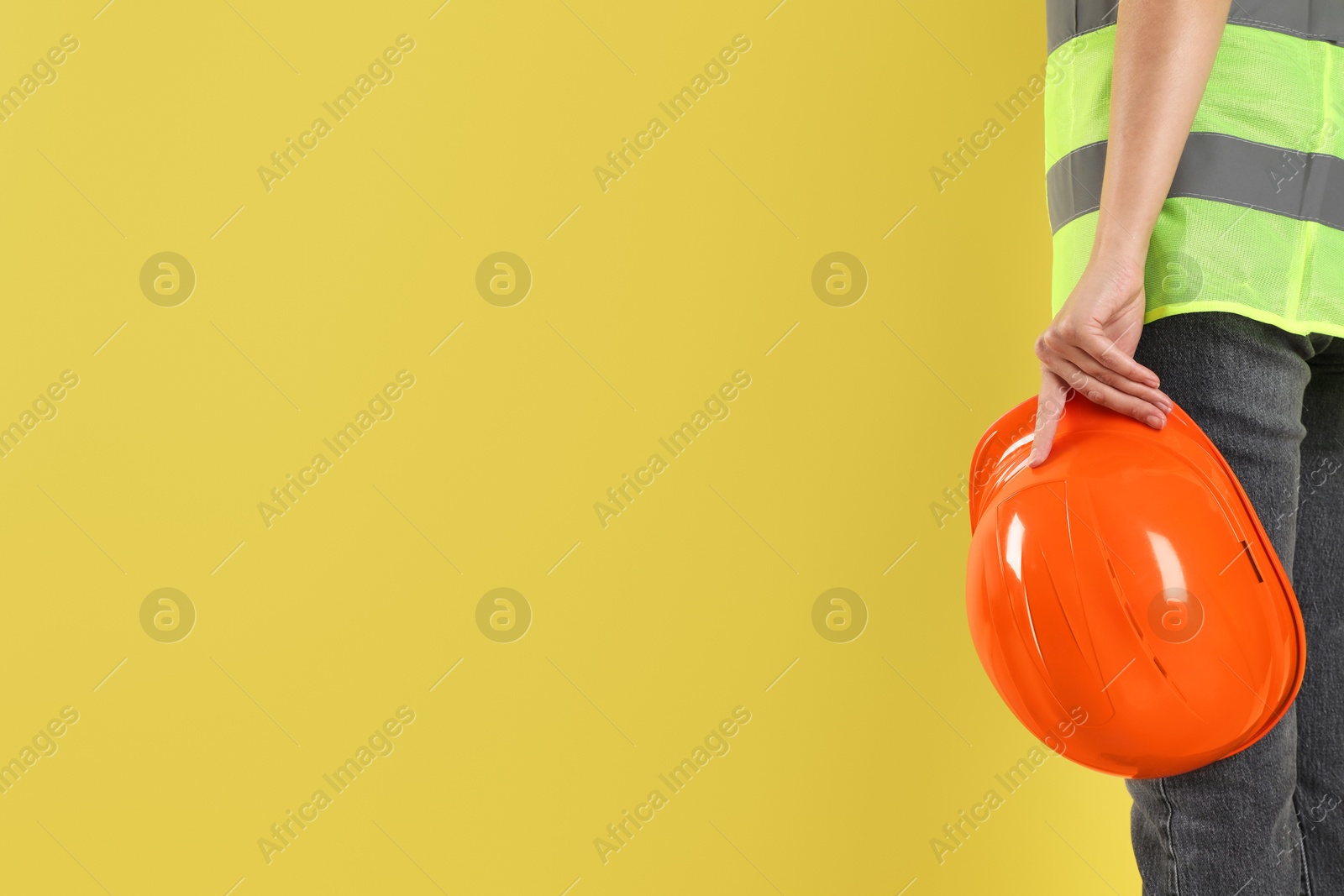 Photo of Engineer with hard hat on yellow background, closeup. Space for text