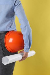 Photo of Engineer with hard hat and draft on yellow background, closeup