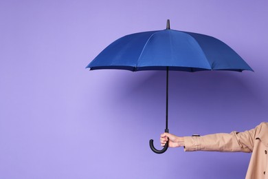 Man holding blue umbrella on purple background, closeup. Space for text