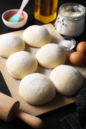 Raw dough balls, yolk, flour, eggs and rolling pin on table