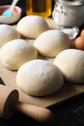 Photo of Raw dough balls and rolling pin on table