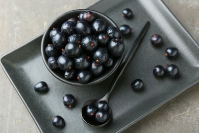 Ripe black currants with water drops on grey table, above view