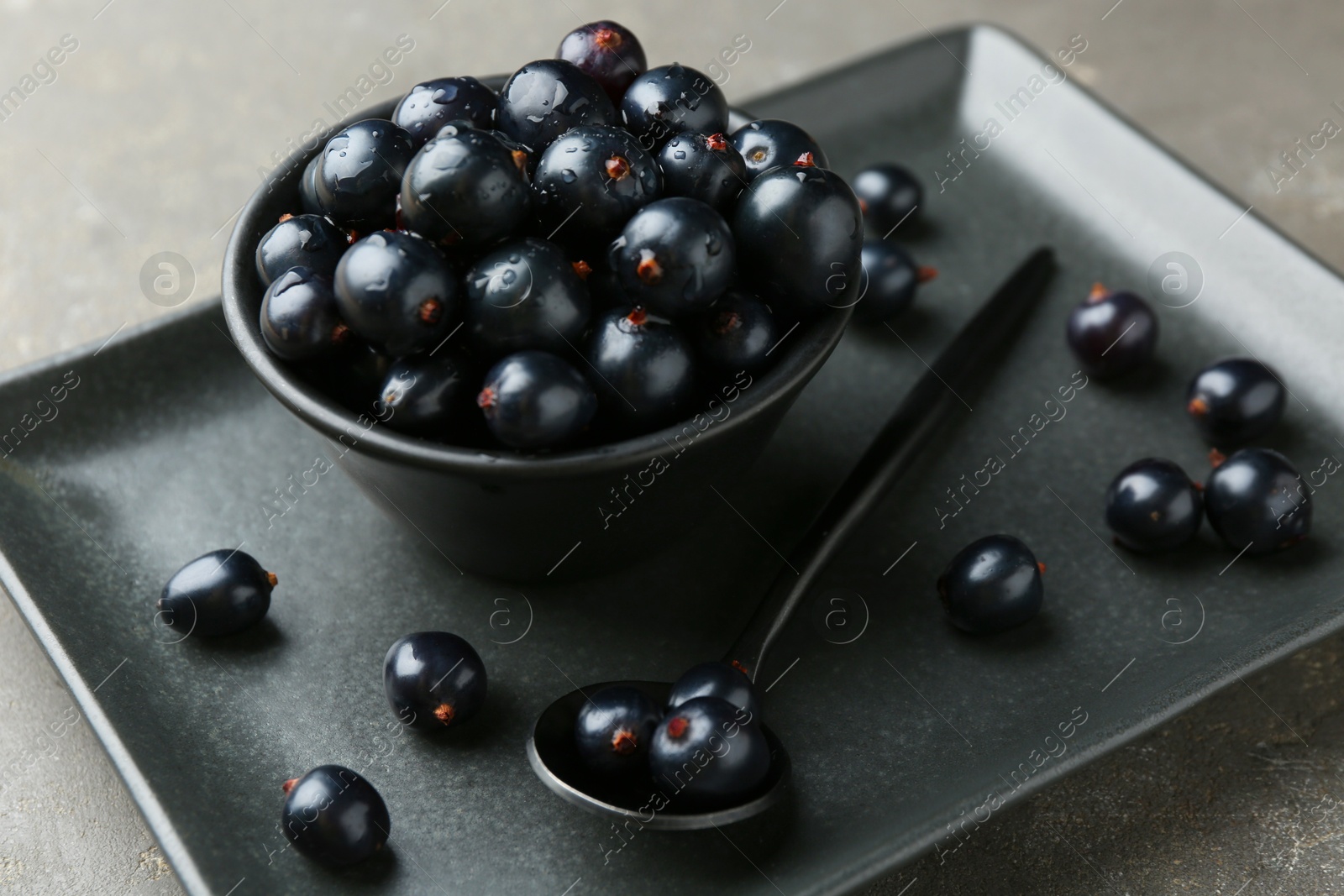 Photo of Ripe black currants with water drops on grey table