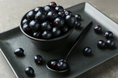 Ripe black currants with water drops on grey table