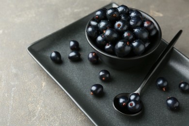 Photo of Ripe black currants with water drops on grey table