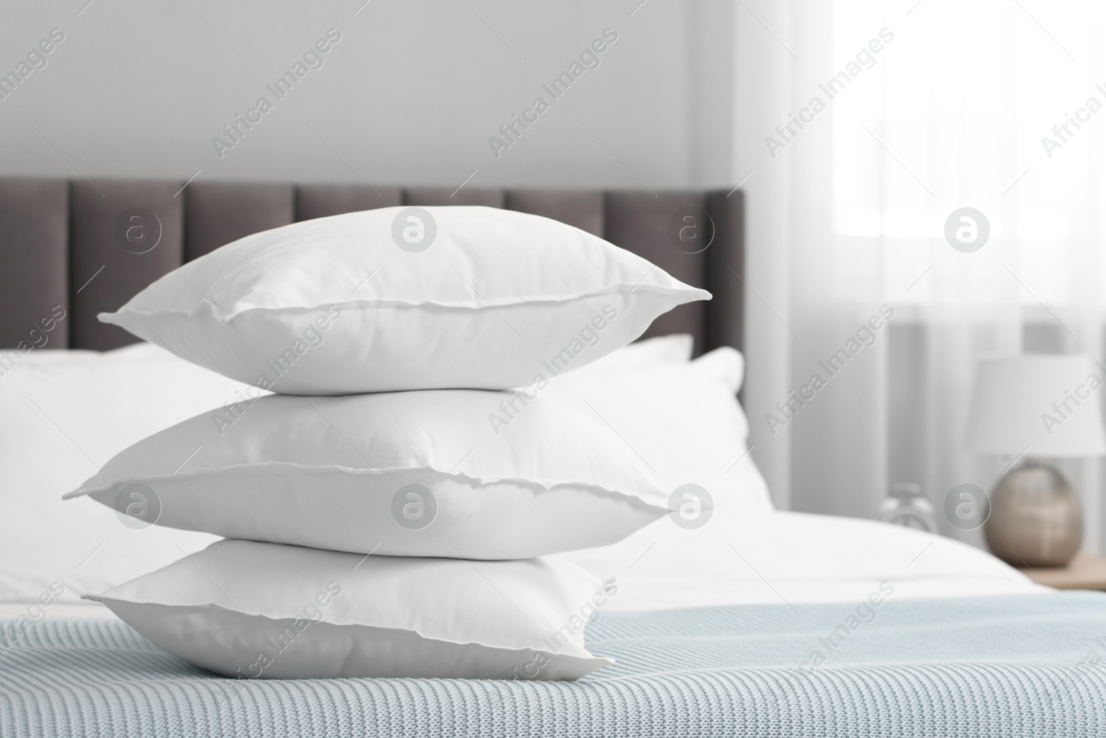 Photo of Many soft pillows on bed at home