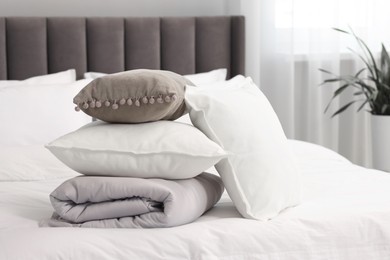 Photo of Soft pillows, cushion and duvet on bed at home