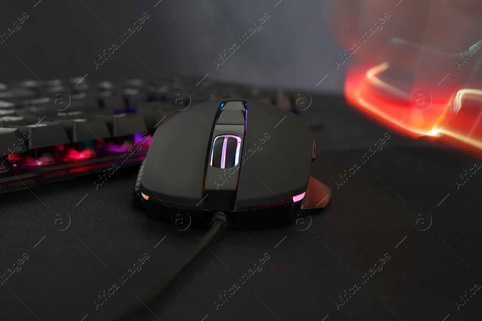 Photo of Computer mouse and RGB keyboard on dark background, closeup