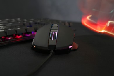 Photo of Computer mouse and RGB keyboard on dark background, closeup