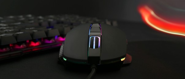 Photo of Computer mouse and RGB keyboard on dark background, closeup