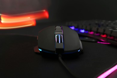 Photo of Computer mouse and RGB keyboard on dark background, closeup