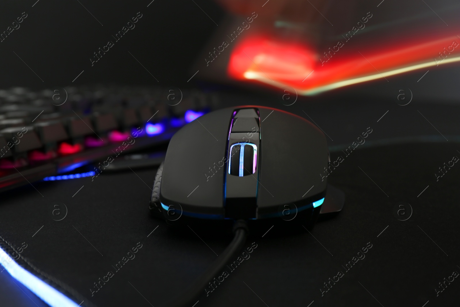 Photo of Computer mouse and RGB keyboard on dark background, closeup