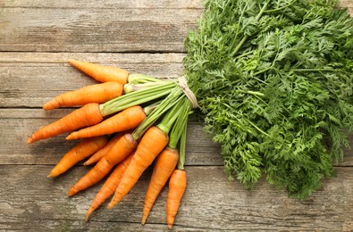 Bunch of tasty ripe juicy carrots on wooden table, top view