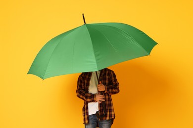 Photo of Little boy with green umbrella on orange background