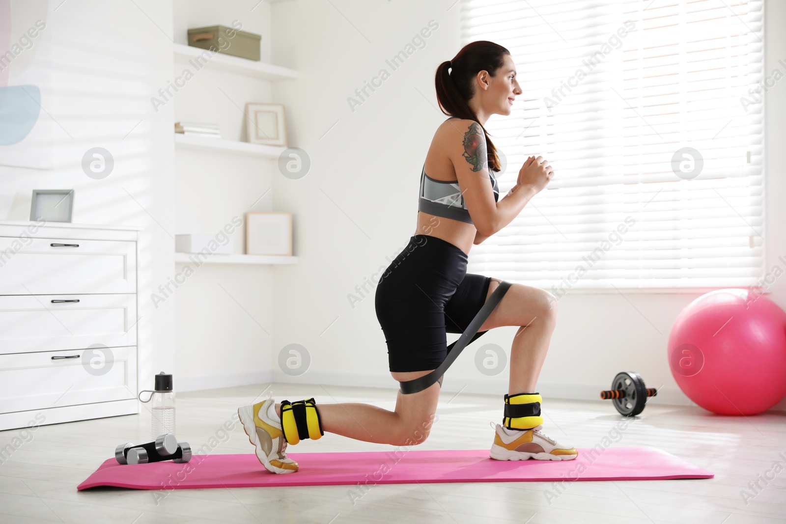 Photo of Woman with ankle weights and elastic band training indoors