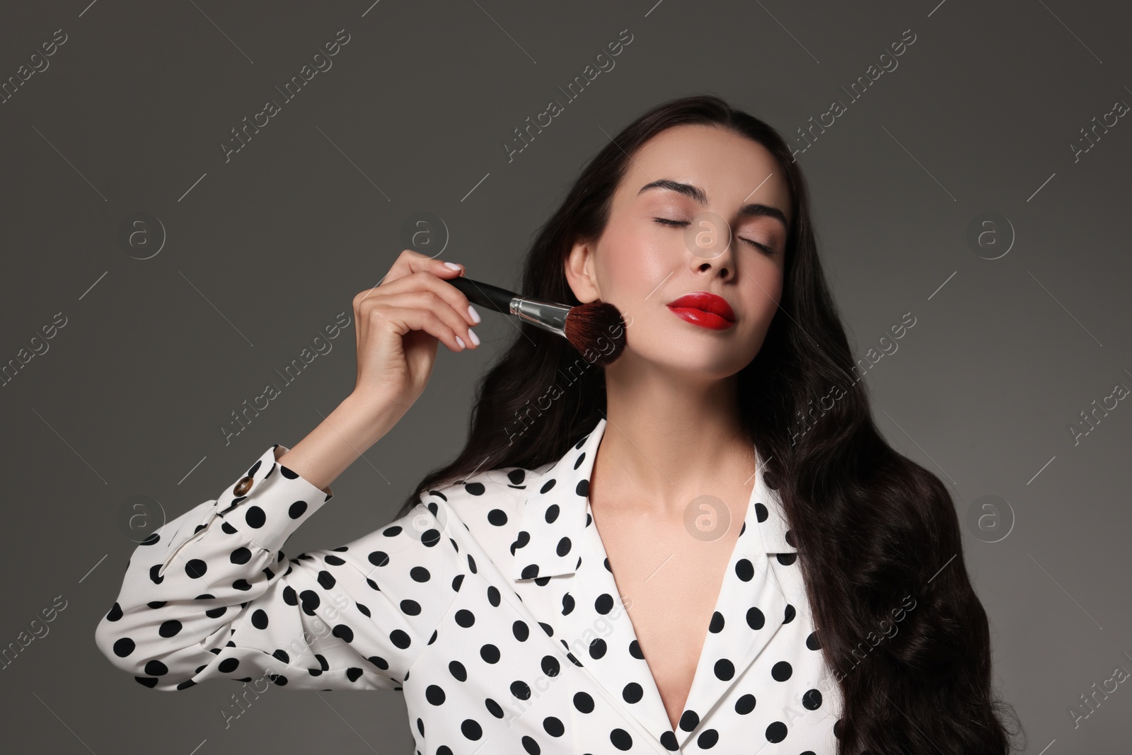 Photo of Beautiful makeup. Attractive woman with brush on grey background