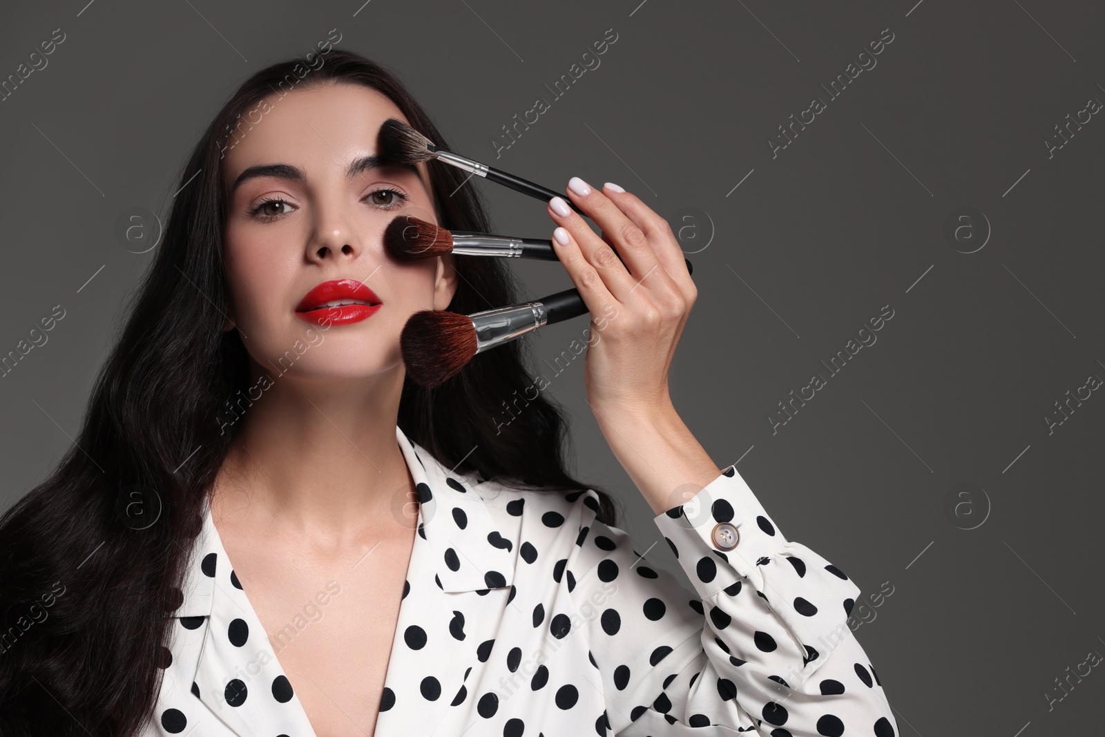 Photo of Beautiful makeup. Attractive woman with brushes on grey background, space for text