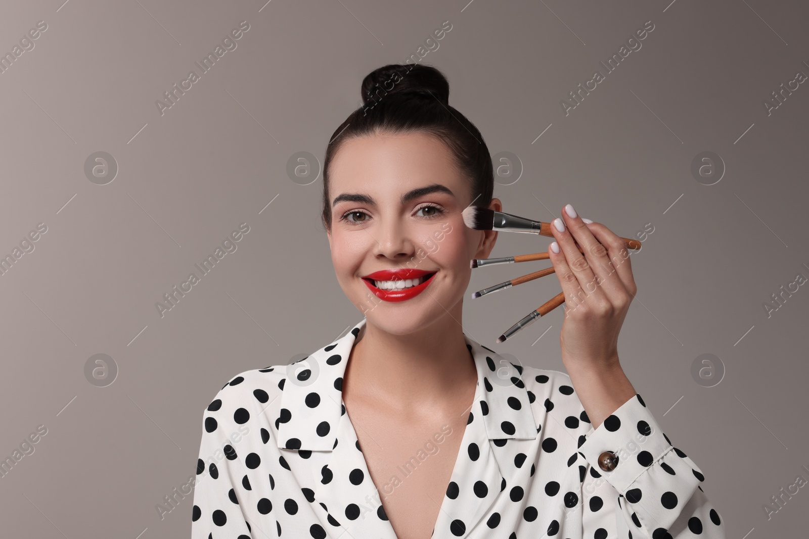 Photo of Beautiful makeup. Smiling woman with brushes on grey background