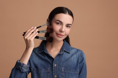 Photo of Beautiful makeup. Attractive woman with brushes on beige background