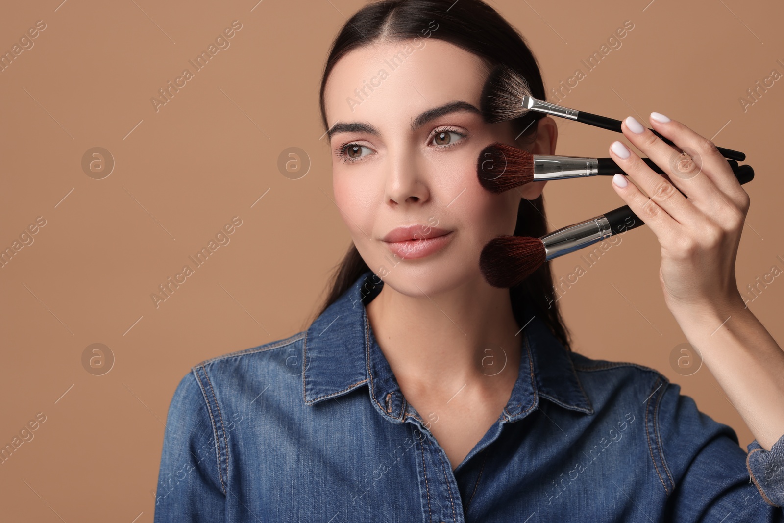 Photo of Beautiful makeup. Attractive woman with brushes on beige background