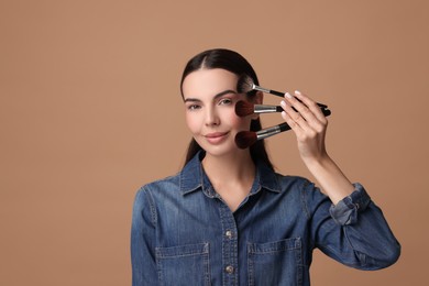 Photo of Beautiful makeup. Attractive woman with brushes on beige background