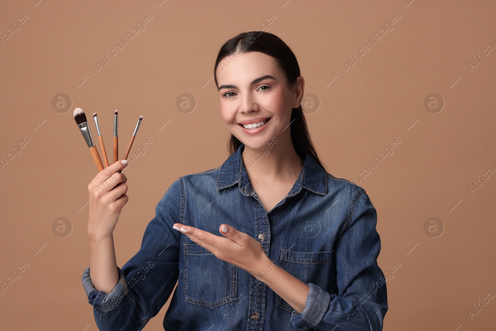 Photo of Beautiful makeup. Attractive woman with brushes on beige background