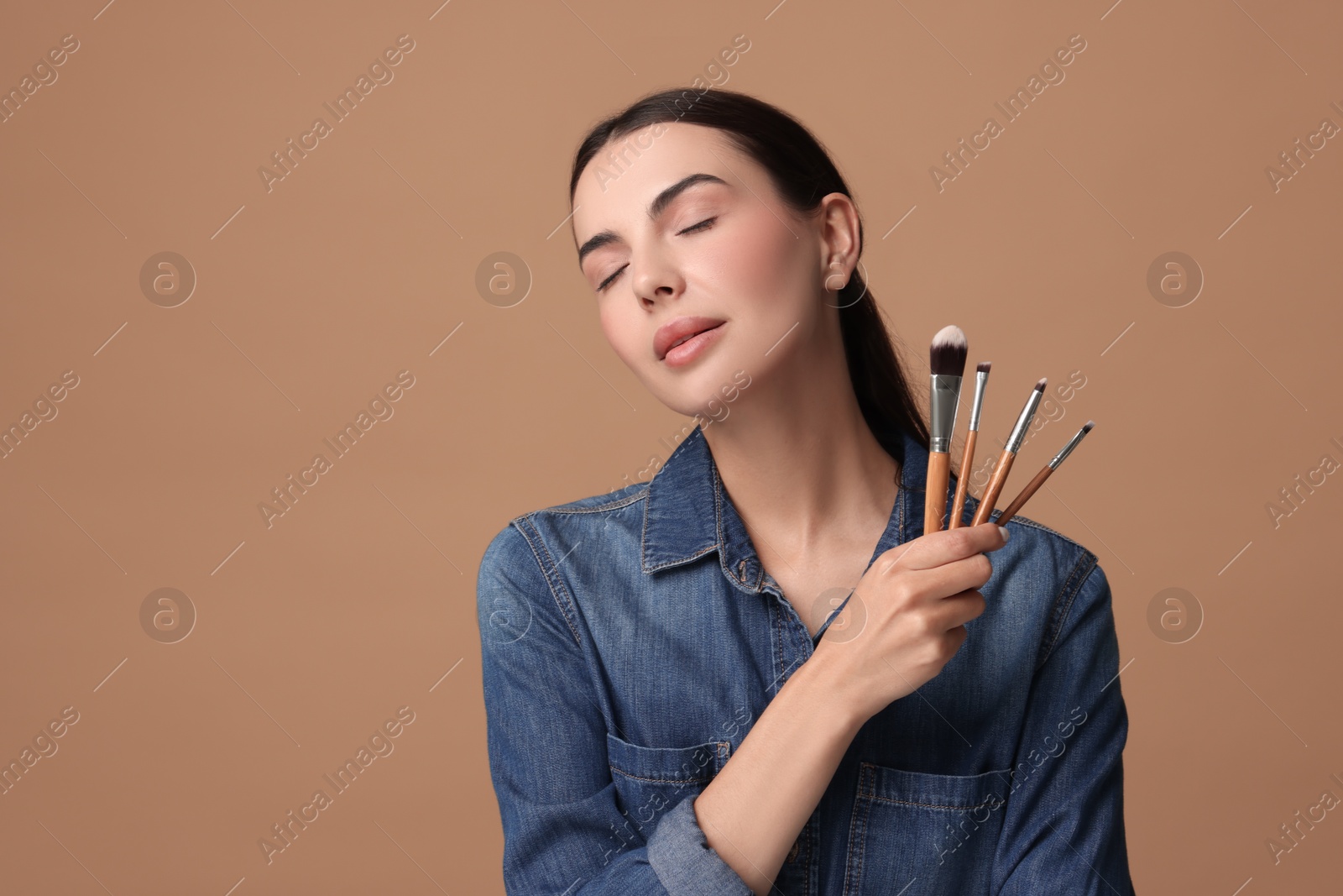 Photo of Beautiful makeup. Attractive woman with brushes on beige background, space for text