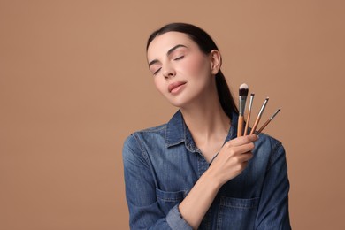 Beautiful makeup. Attractive woman with brushes on beige background, space for text