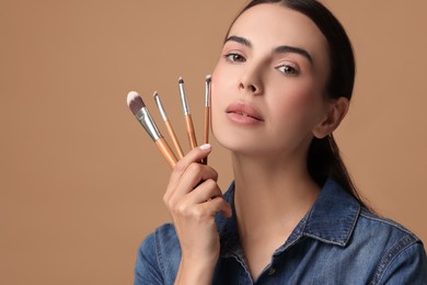 Photo of Beautiful makeup. Attractive woman with brushes on beige background, space for text