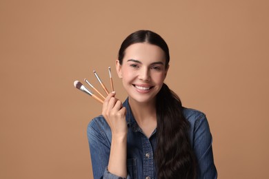 Photo of Beautiful makeup. Smiling woman with brushes on beige background