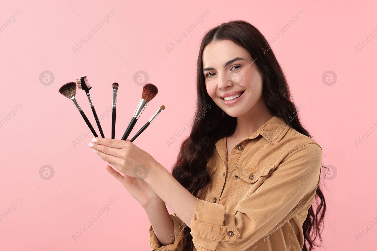 Photo of Beautiful makeup. Smiling woman with brushes on pink background