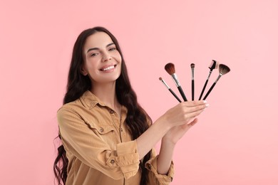 Beautiful makeup. Smiling woman with brushes on pink background