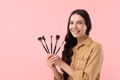 Photo of Beautiful makeup. Smiling woman with brushes on pink background, space for text