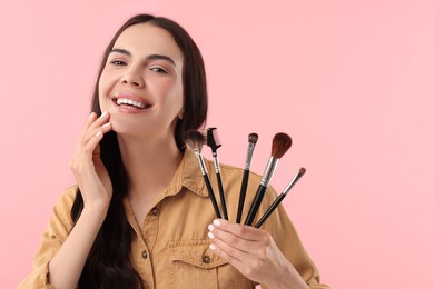 Beautiful makeup. Smiling woman with brushes on pink background, space for text