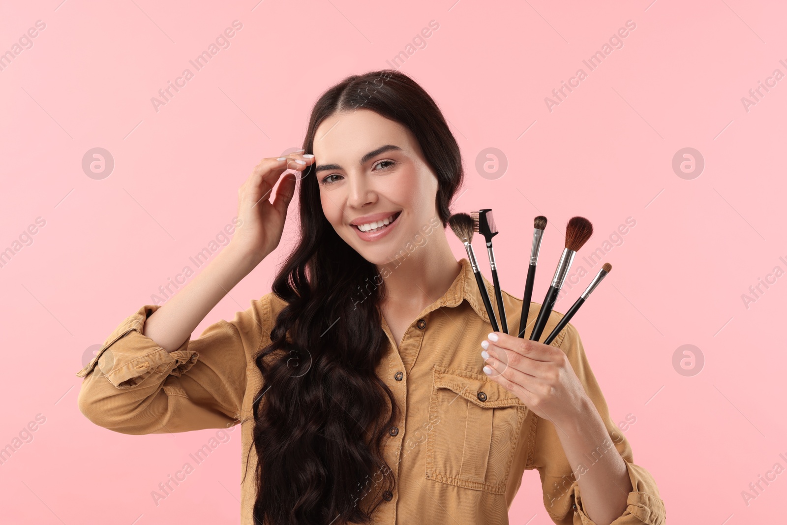 Photo of Beautiful makeup. Smiling woman with brushes on pink background