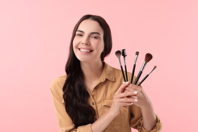 Beautiful makeup. Smiling woman with brushes on pink background