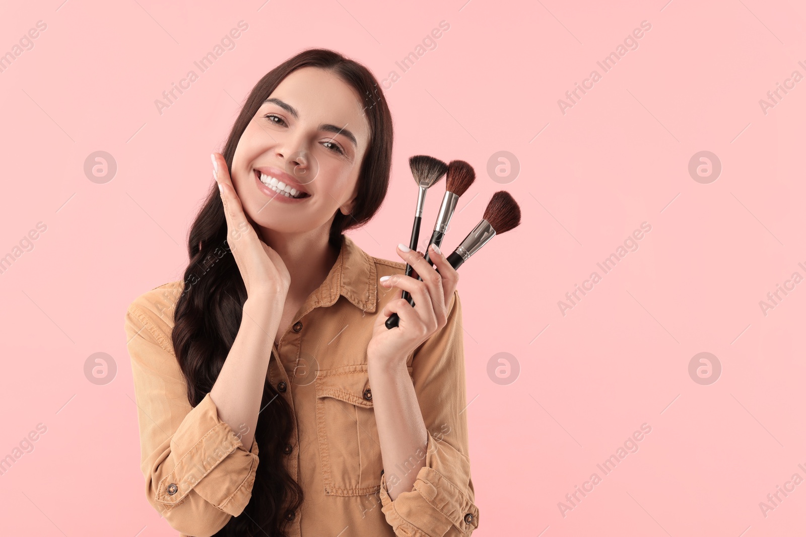 Photo of Beautiful makeup. Smiling woman with brushes on pink background, space for text