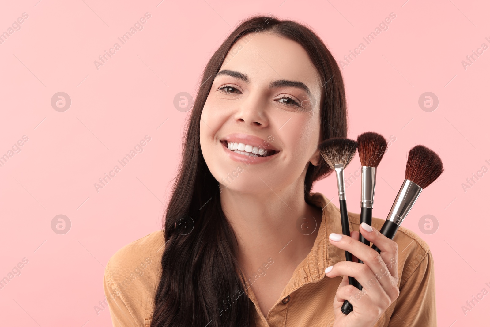 Photo of Beautiful makeup. Smiling woman with brushes on pink background