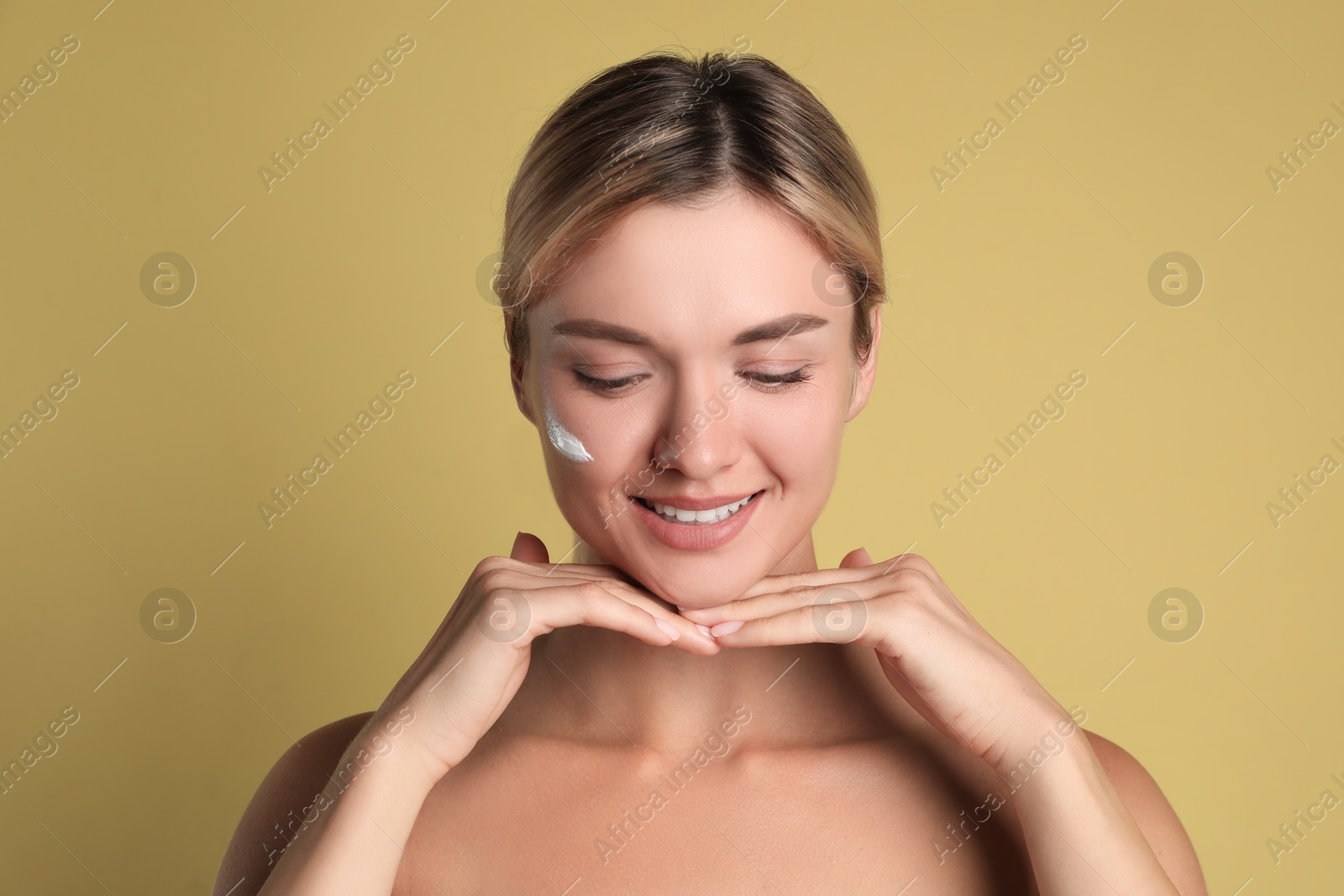 Photo of Beautiful woman with cream on her face against olive background