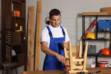 Man repairing wooden stool with screwdriver indoors