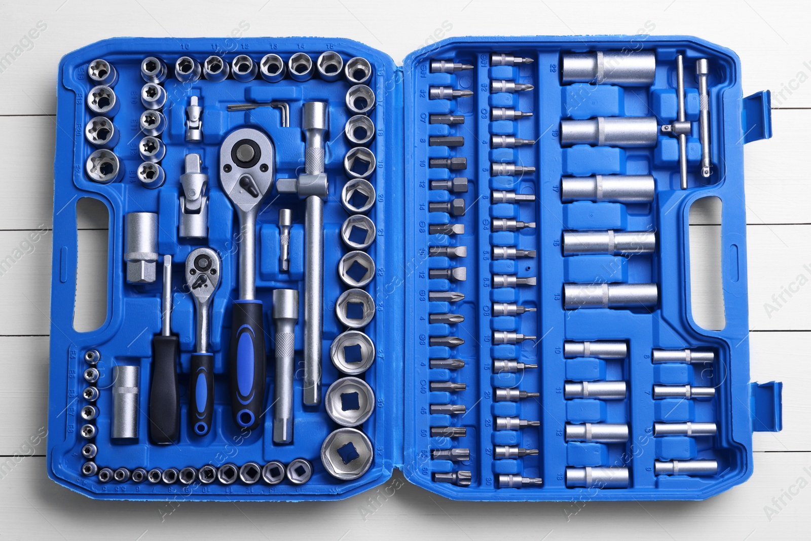 Photo of Auto mechanic's tools in plastic box on white wooden table, top view