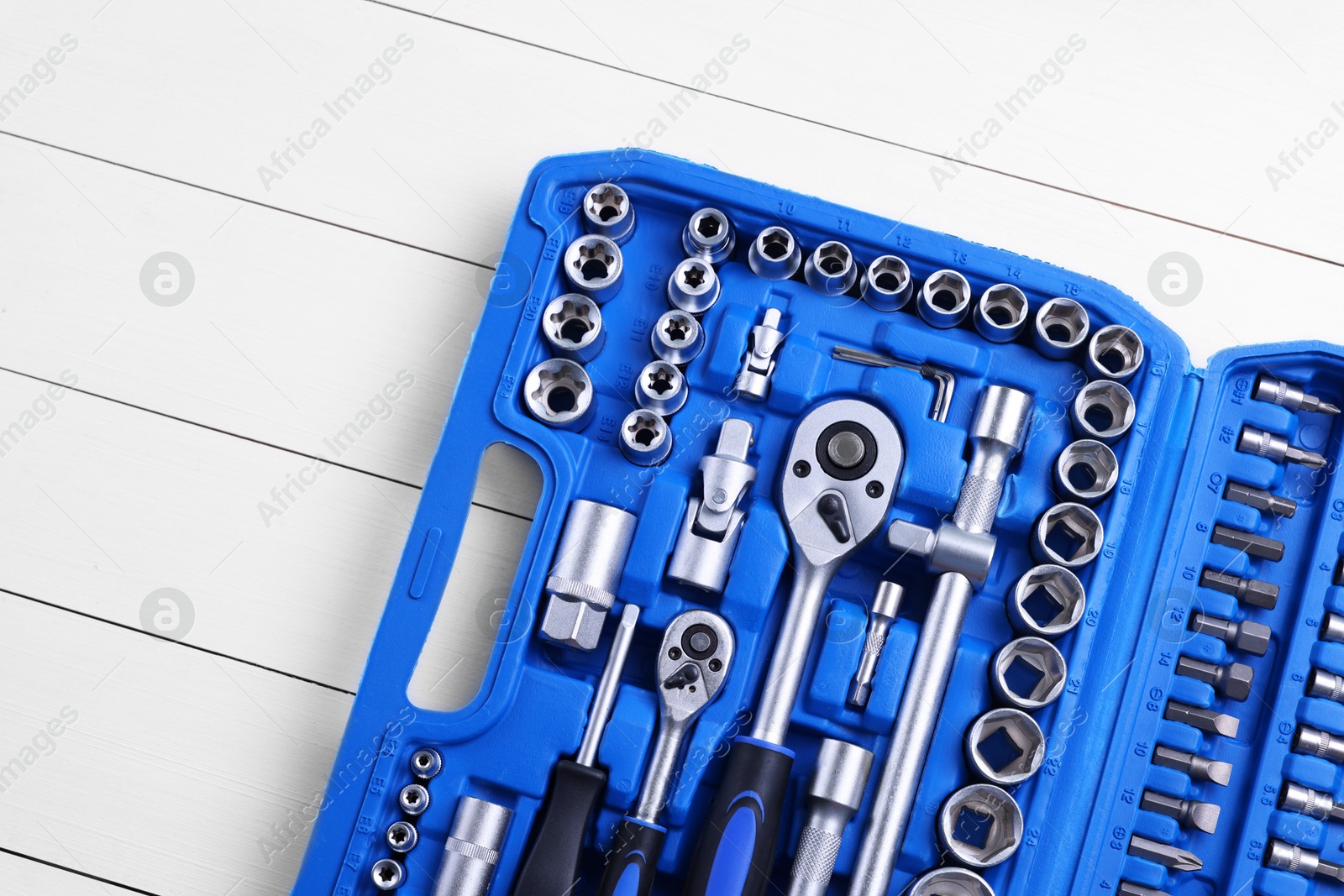 Photo of Auto mechanic's tools in plastic box on white wooden table, top view. Space for text