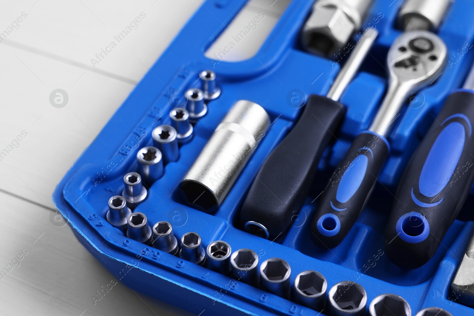 Photo of Auto mechanic's tools in plastic box on white wooden table, closeup