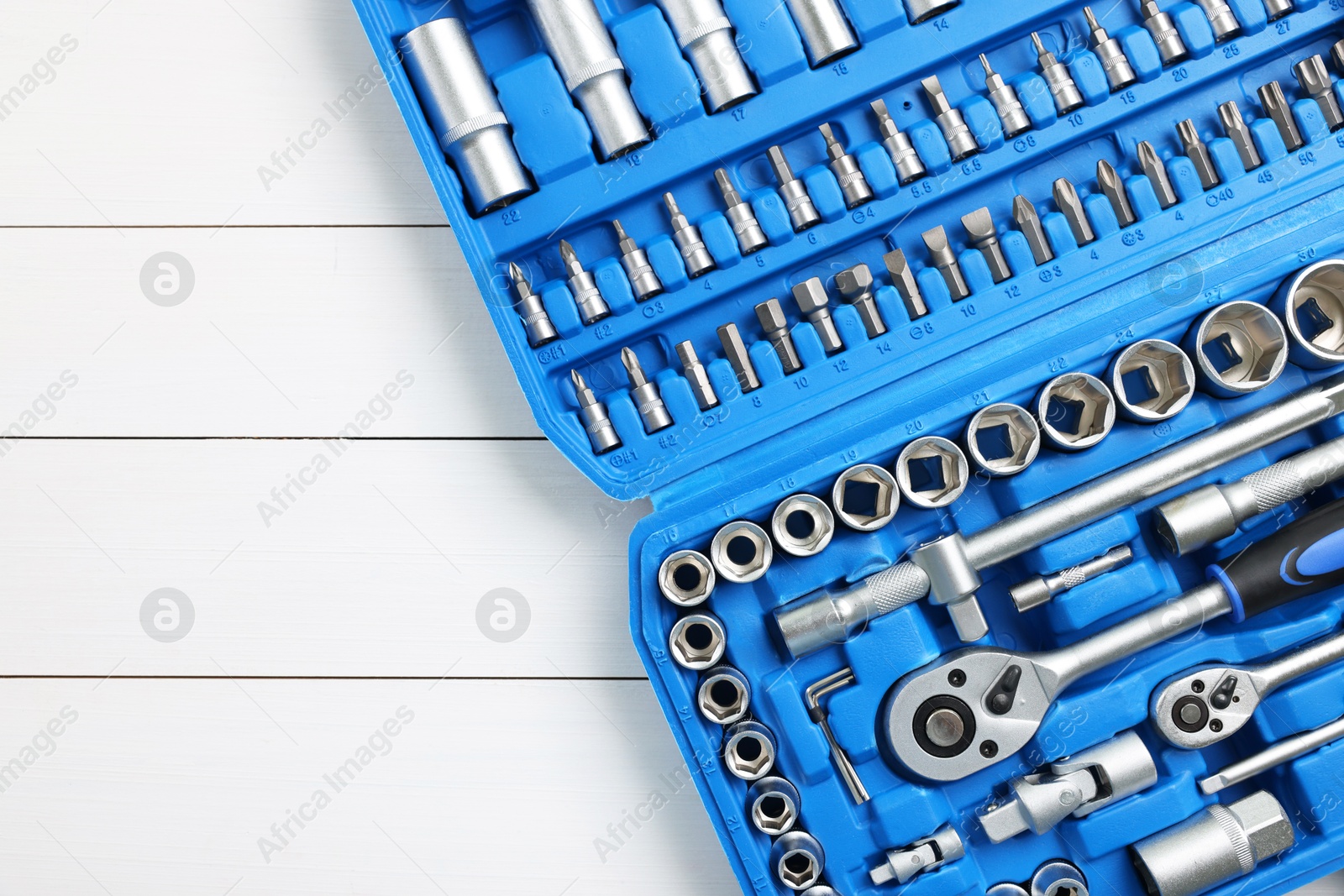 Photo of Auto mechanic's tools in plastic box on white wooden table, top view. Space for text