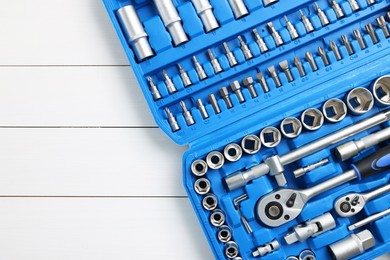 Photo of Auto mechanic's tools in plastic box on white wooden table, top view. Space for text