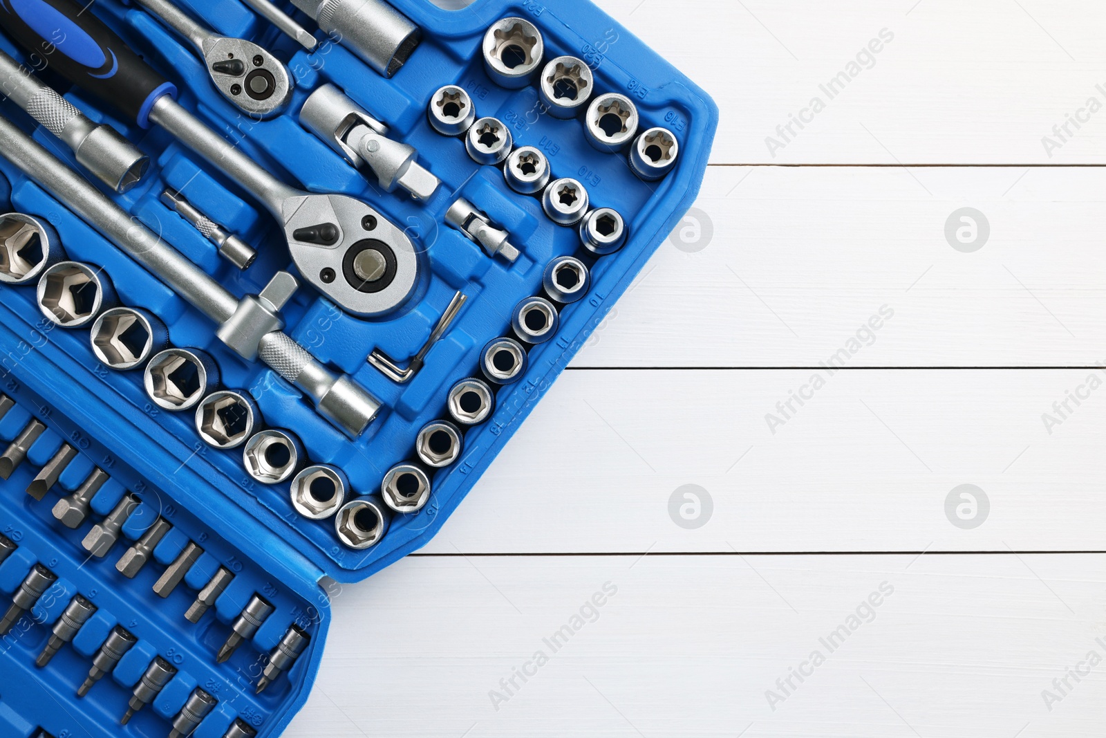 Photo of Auto mechanic's tools in plastic box on white wooden table, top view. Space for text