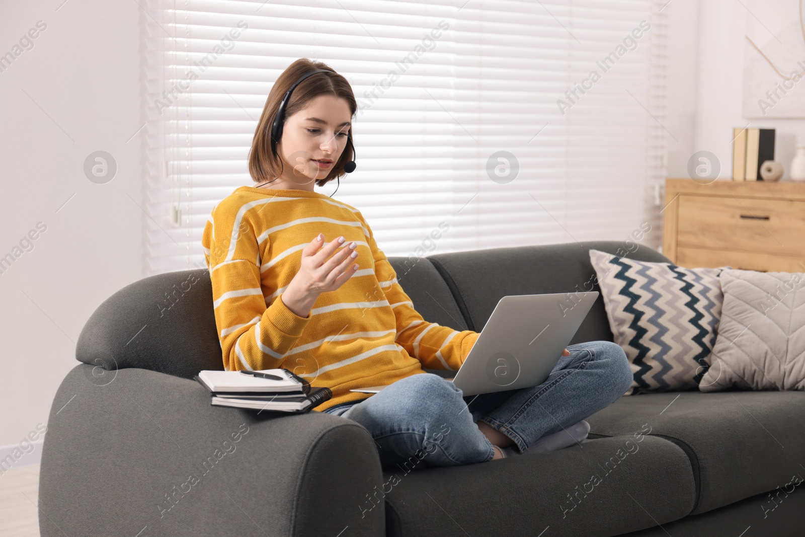 Photo of Teenager in headset having video chat via laptop at home. Remote work